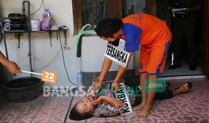 Tersangka saat memperagakan adegan mencekik korban. foto: AAN AMRULLOH/ BANGSAONLINE