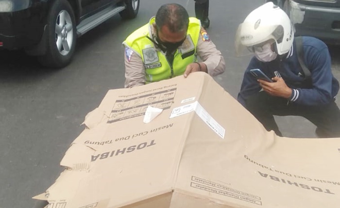 Jenazah korban ditutup dengan lembaran kardus sedang diperiksa petugas.