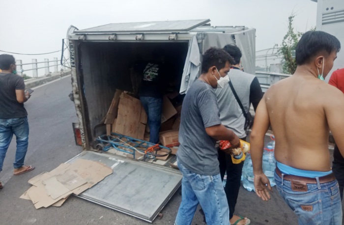 Petugas melakukan evakuasi galon mineral dengan cara dikeluarkan dari boks truk lalu dipindahkan ke truk boks yang lain.