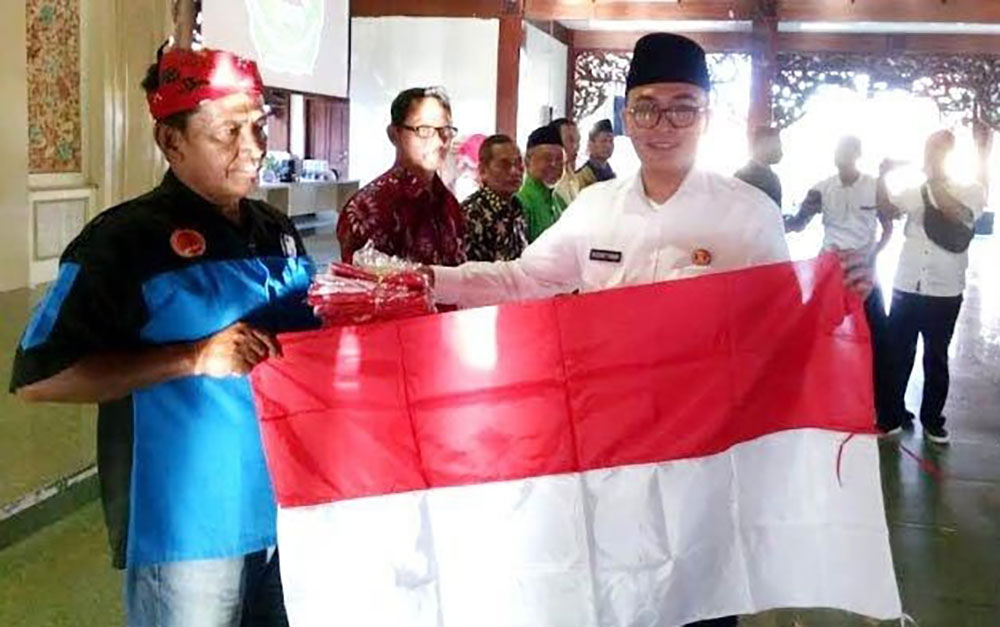 Bupati Pamekasan H. Baddrut Tamam saat secara simbolis menyerahkan bendera merah-putih kepada perwakilan warga. 
