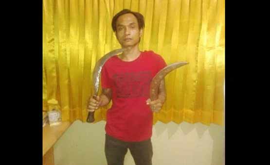SAKIT HATI: Tersangka Doni memamerkan celurit yang dipakai menyabet punggung atasannya. foto: realita