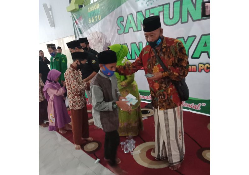 Tampak Ketua PCNU Bangil H. M. Shobri saat membagikan uang kepada anak yatim.