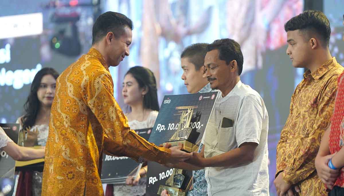 Direktur Pengembangan Bisnis dan Strategy SIG, Dennis Pratistha, saat menyerahkan trofi penghargaan kategori Toko Best Loyalty kepada pemilik Toko Bangunan Dua Ribu, Kabupaten Malang, Amin. Foto: Ist