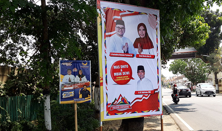 Banner Dhito-Dewi yang ada foto Ir. H. Sutrisno, M.M., yang ditempel dengan menutup gambar lain, yaitu banner milik Golkar di Jalan Raya Kediri-Pare Kecamatan Gurah, Kabupaten Kediri. (foto: MUJI H/ BANGSAONLINE)
