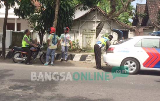 Petugas Satlantas Polres Kediri Kota saat memberikan surat tilang kepada dua pelajar yang sedang merayakan kelulusan. foto: arif kurniawan/ BANGSAONLINE
