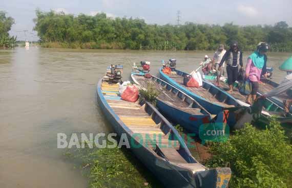 Masyarakat tetap beraktivitas melakukan penyeberangan dengan perahu kayu meski kondisi air Sungai Bengawan Solo sedang naik. foto: EKY NURHADI/ BANGSAONLINE