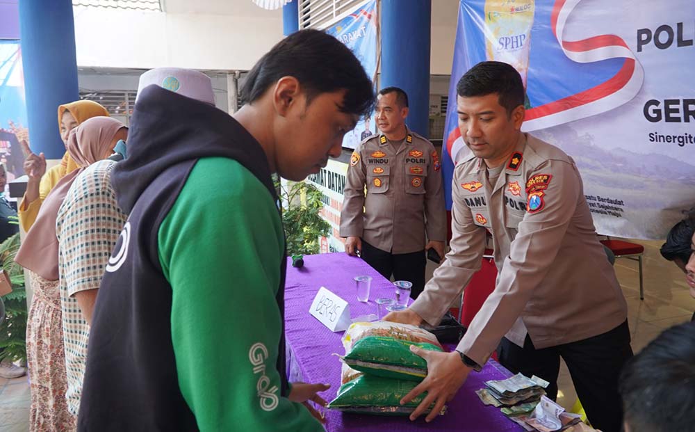 Wakapolres Gresik Kompol Danu Anindhito (kanan) melayani pembeli di gelaran pangan murah. Foto: Ist.
