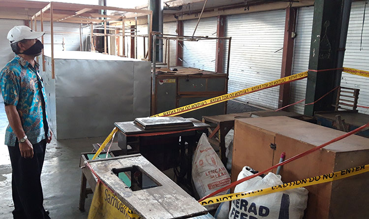 Soewardi, Koordinator Pasar Pahing Kota Kediri saat mengecek lapak pasien positif Covid-19 yang sudah dipasangi garis polisi. (foto: MUJI/ BANGSAONLINE)