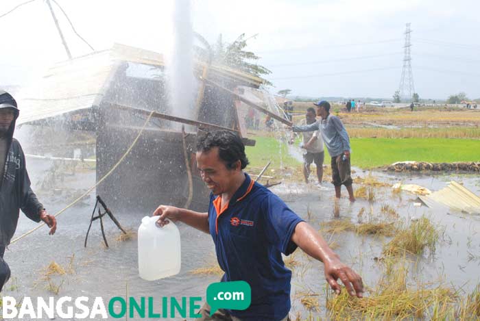 Sejumlah warga menampung semburan air menggunakan jerigen untuk dibawa pulang. foto: ZAINAL/ BANGSAONLINE