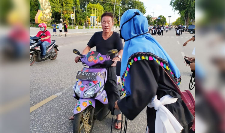 Anggota PSHT Sumenep membagikan masker kepada pengguna jalan yang melintas di depan Masjid Jamik Sumenep.