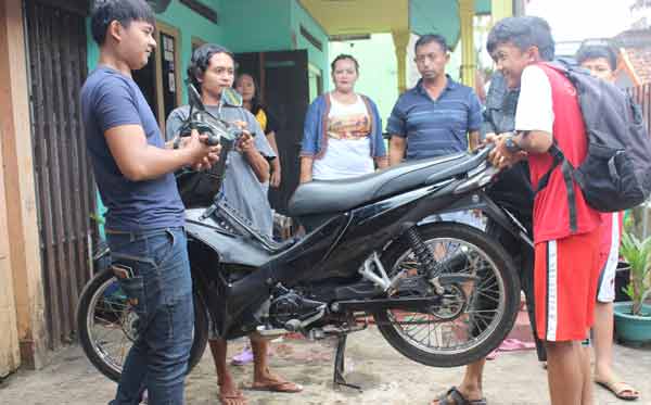 Keempat pemuda menunjukkan aksinya mengangkat motor dengan dua jari usai membasuh tangannya menggunakan air rendaman batu Marantale. (foto: khumaidi/BANGSAONLINE)