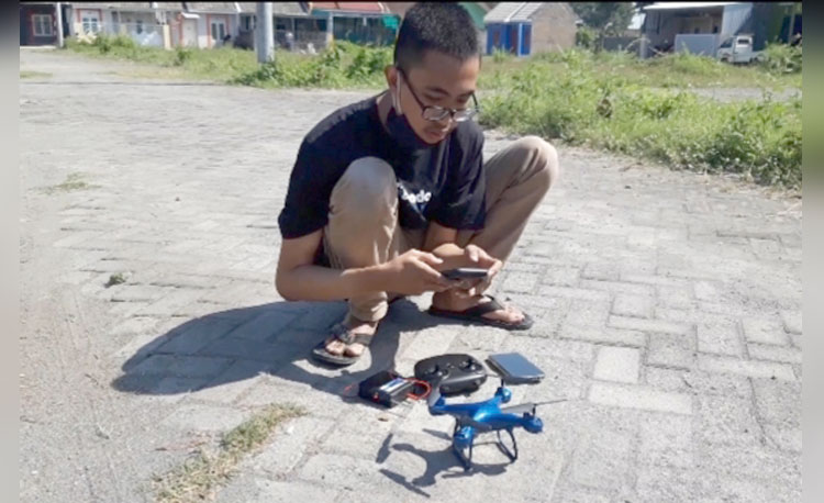 Muhamad Azhar Syahrudin saat akan menguji coba drone ciptaannya yang sebagian komponennya menggunakan barang bekas. foto: MUJI HARJITA/ BANGSAONLINE