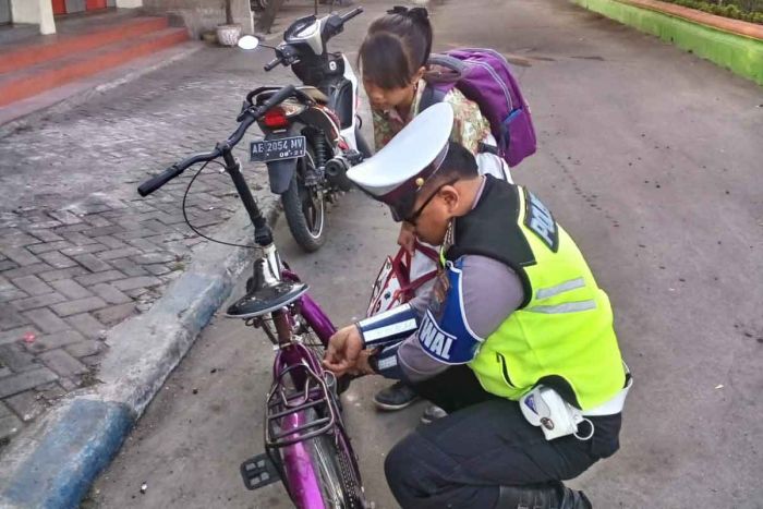 Lakukan Pengamanan Pagi, Anggota Satlantas Polres Ngawi Betulkan Sepeda Pelajar