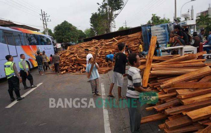 Truk Terguling di depan SPBU Tambak Beras Jombang, Ribuan Balok Kayu Mahoni Berserakan