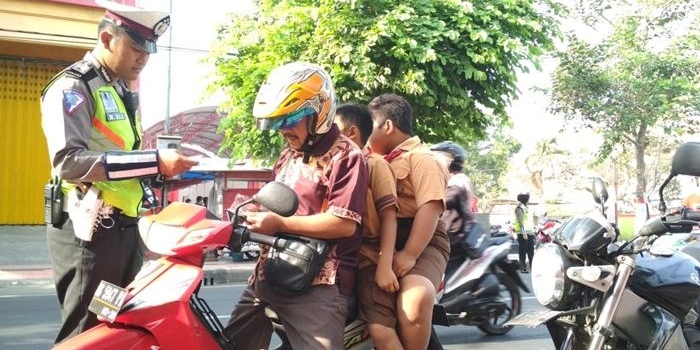 Petugas saat menilang seorang pengendara yang juga berboncengan tiga.