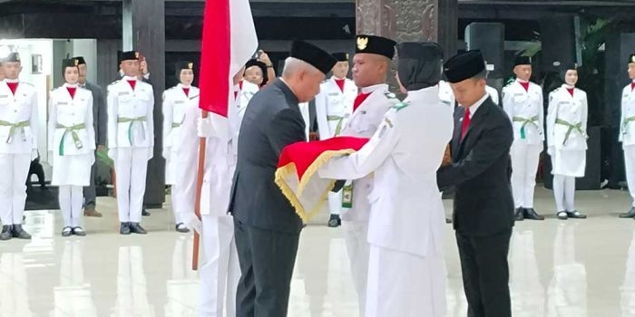 Pj Bupati Nganjuk Sri Handoko Taruna saat menyematkan sabuk dalam pengukuhan Paskibraka 2024. 
