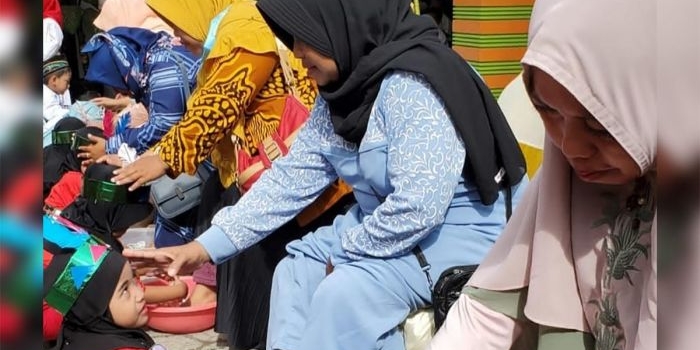 Siswa PAUD At-Tin saat membasuh kaki ibunya. Foto: AAN AMRULLOH/ BANGSAONLINE