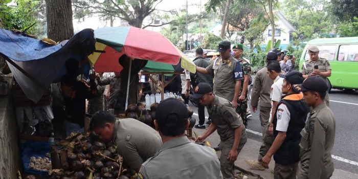 Petugas gabungan saat melakukan penertiban lapak PKL yang berada di sejumlah wilayah terlarang di Kota Batu, Kamis (9/5/2024).