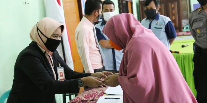 Petugas saat menyerahkan BLT kepada salah satu warga terdampak Covid-19 di Desa Janti, Kecamatan Papar, Kabupaten Kediri. foto: ist