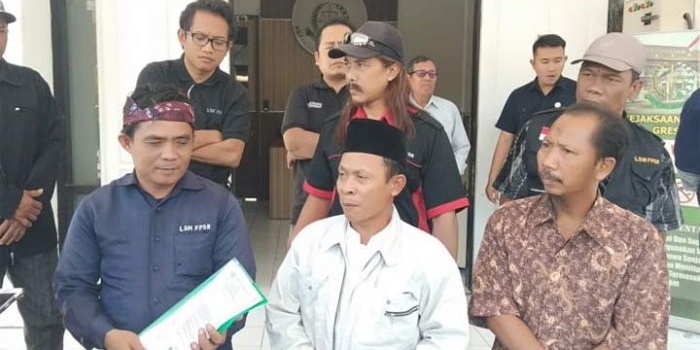 Ketua AMPTN Desa Kedamean Nur Qomari (tengah) memberikan keterangan usai melaporkan mantan Kades Kedamean ke Kejari Gresik. foto: SYUHUD/ BANGSAONLINE