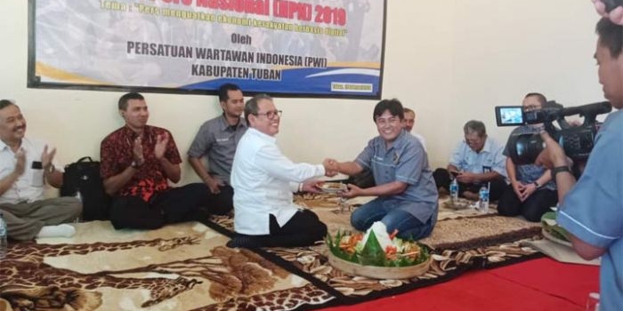 Wabup Noor Nahar Hussein menerima potongan tumpeng dari Ketua PWI Tuban Pipit Wibawanto.