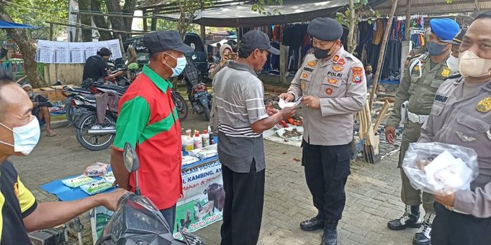 Petugas gabungan saat membagikan masker dalam giat pamor keris, Rabu (9/2).