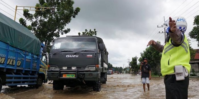 Petugas mengatur pengalihan lalu lintas akibat jalan yang tergenang banjir di Bandar Kedungmulyo, Jombang.