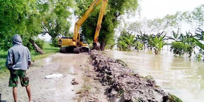 Alat backhoe dikerahkan untuk bikin tanggul darurat. foto: eky nurhadi/BANGSAONLINE