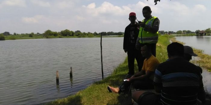 Petugas Polsek Jabon bersama warga dan keluarga korban menunggu di area tambak. 
