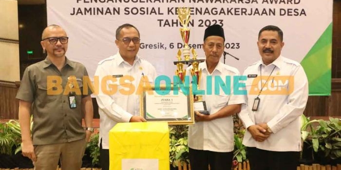 Sekdakab Gresik, Achmad Washil Miftahul Rachman, saat menyerahkan tropi kepada pemenang Nawakarsa Award Jaminan Sosial Ketenagakerjaan Desa tahun 2023. Foto: SYUHUD/BANGSAONLINE
