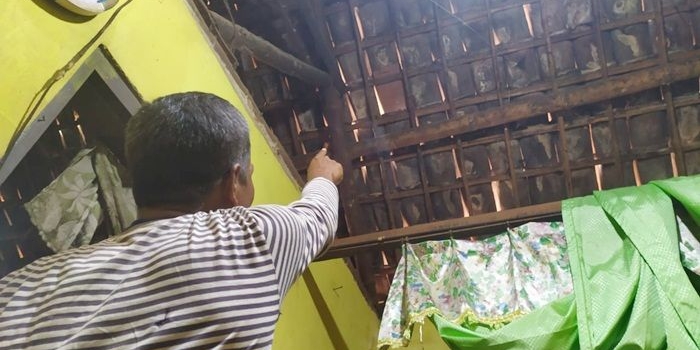 Suparno saat menunjukkan lokasi lemparan batu pada genting dapurnya.
