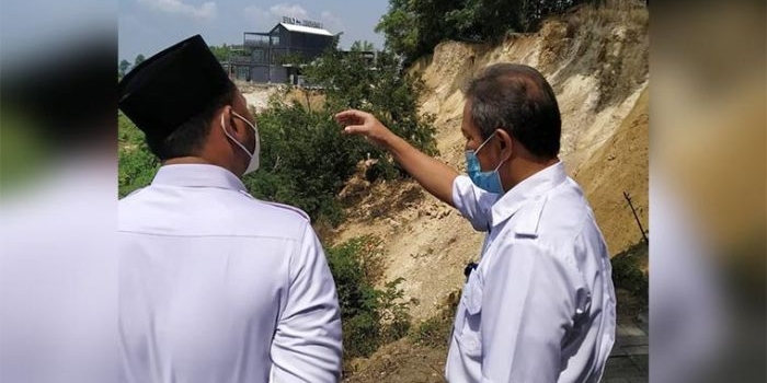 Kepala DPUTR Gresik Gunawan Setijadi (kanan) menerangkan kondisi longsor Bukit Pucem kepada Bupati Gus Yani. foto: ist.