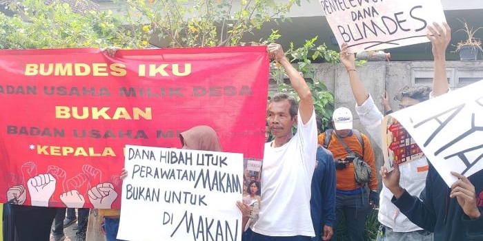 Warga Desa Boro saat membentangkan spanduk saat menggelar aksi protes