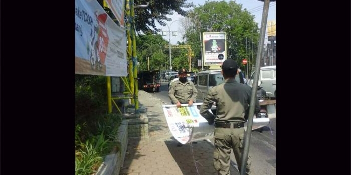 Petugas Dispol PP ketika mencopot spanduk liar di salah satu titik jalan protokol.