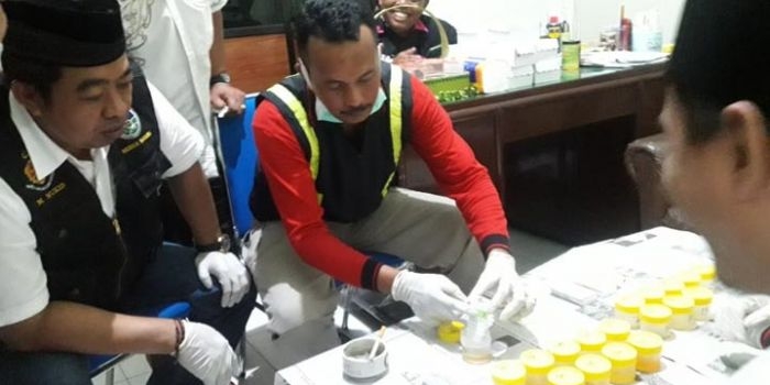 Petugas saat melakukan cek urine di kantor Desa Candimulyo. foto: AAN AMRULLOH/ BANGSAONLINE