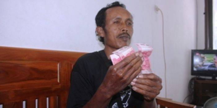 Amik Anwar ketika menunjukkan uang sogokkan dari oknum perangkat desa, agar tutup mulut. (Suwandi/BANGSAONLINE)
