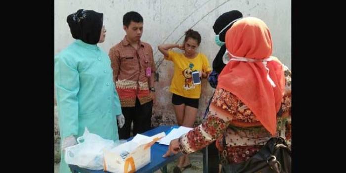 Pegawai Dinas Kesehatan Kota Blitar tengah memeriksa urine salah satu penghuni kos. foto: tri susanto/ BANGSAONLINE