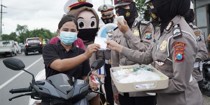 Jajaran kepolisian dari Polres Mojokerto Kota tengah membagikan masker di Jalur Perbatasan Mojokerto-Lamongan. foto: YUDI EP/ BANGSAONLINE