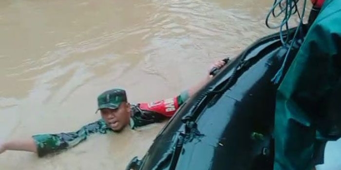 Babinsa Koramil 0818/16 Sumawe, Serda Siwo, saat berenang menyalurkan bantuan berupa makanan untuk korban banjir.
