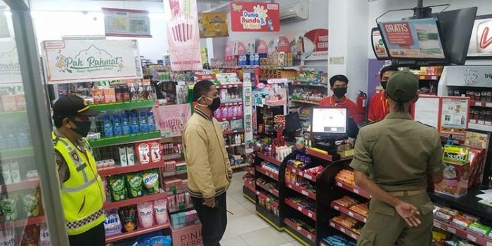 Petugas gabungan saat memberi imbauan tetap jaga jarak dan pakai masker di sebuah toko swalayan. (foto: MUJI/ BANGSAONLINE)