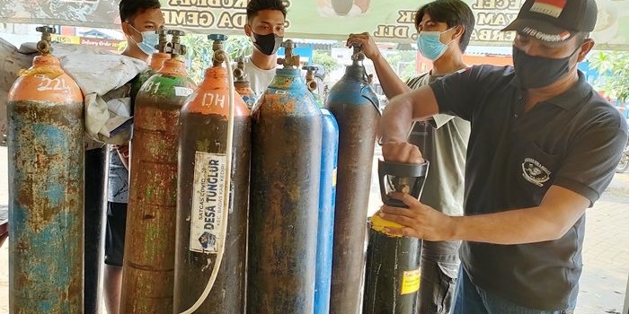 Ali Mashar (kanan) dibantu tim relawan saat melayani permintaan oksigen dari warga. foto: MUJI HARJITA/BANGSAONLINE