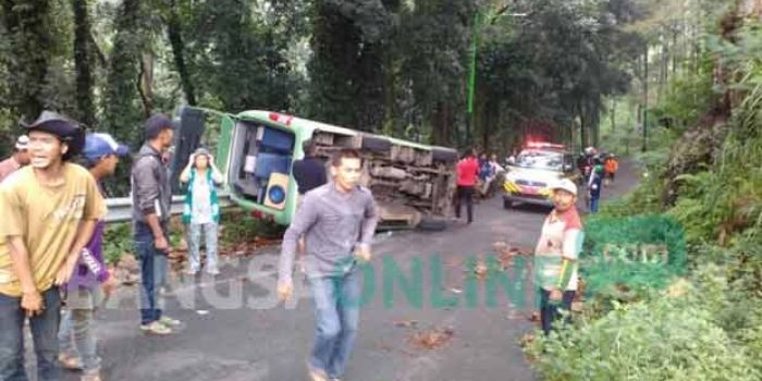 Minibus yang terguling setelah menabrak pembatas jalan.