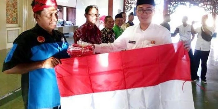 Bupati Pamekasan H. Baddrut Tamam saat secara simbolis menyerahkan bendera merah-putih kepada perwakilan warga. 