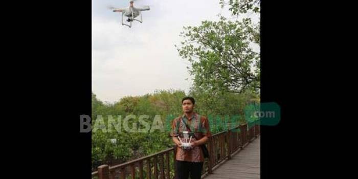 Sanubari Barata mengoperasikan drone di kawasan mangrove, Wonorejo Surabaya. foto: devi fitri/ BANGSAONLINE