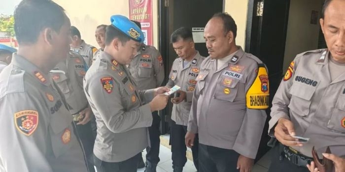 Kasipropam AKP Darsono saat melakukan pengecekan ponsel milik anggota Polsek