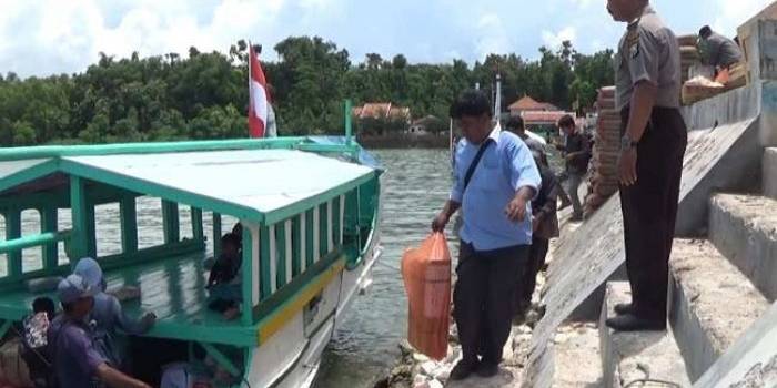 Petugas saat menaikkan naskah Unas ke perahu. foto: rahmatullah/ BANGSAONLINE