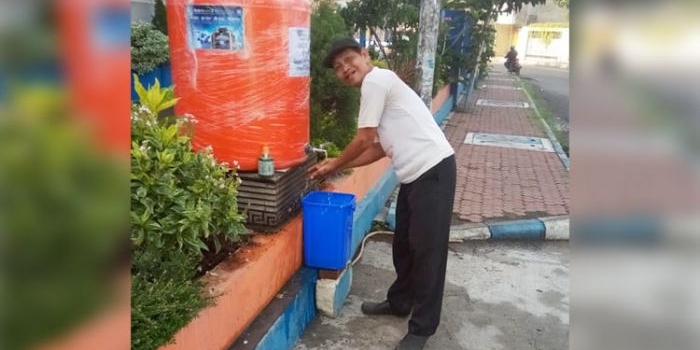 UNTUK UMUM: Seorang warga memanfaatkan fasilitas cuci tangan yang disediakan Smamita Sidoarjo, Rabu (8/4). foto: ist