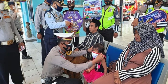 Kasat Lantas Polres Pamekasan AKP Deddy Eka Priyanto saat memasangkan masker kepada anak kecil dan mengharapkan tetap mematuhi protokol kesehatan. (foto: ist)