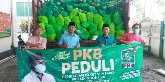 Ketua DPC PKB Bangkalan Ir. Mondir Rofii bersama para pengurus DPC foto dengan latar belakang paket sembako bantuan dari Ketum PKB. foto: SUBAIDAH/ BANGSAONLINE