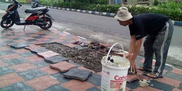 Warga yang khawatir memperbaiki sendiri trotoar yang rusak di depan rumah mereka.
